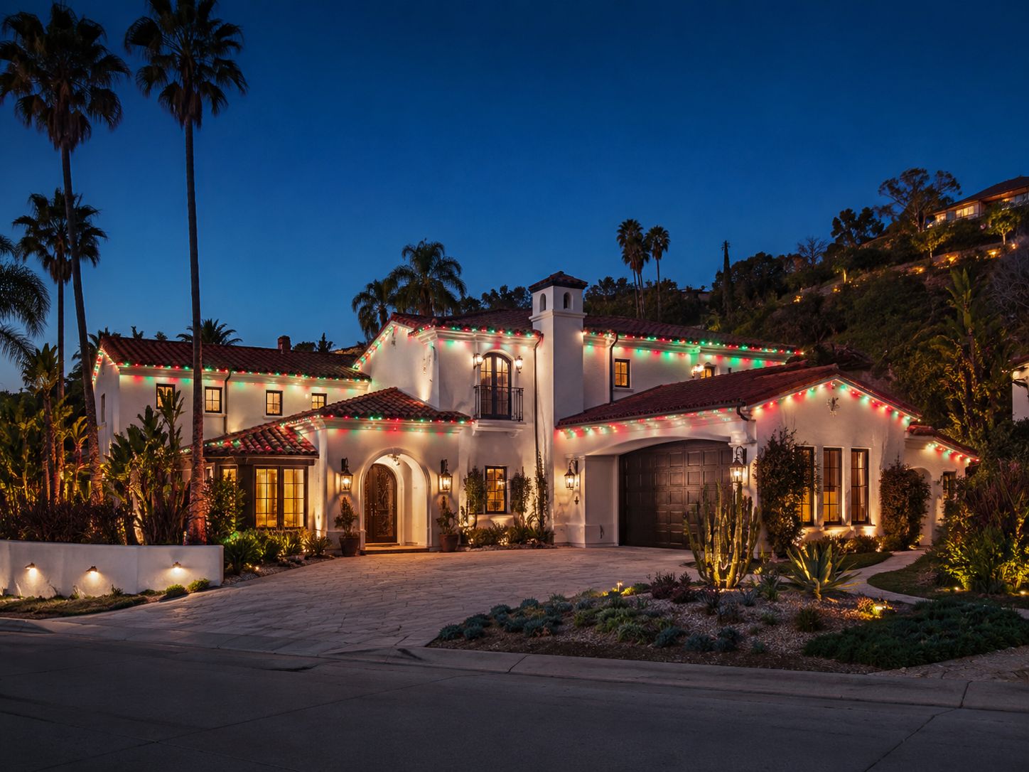 Spanish-style Los Angeles home with red and green permanent roofline lighting at dusk
